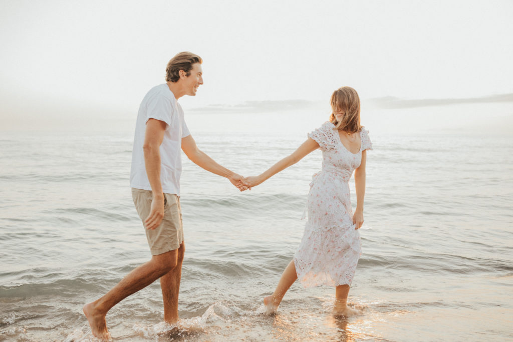 couple holding hands and walking on beach